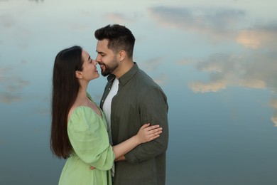 Photo of Romantic date. Beautiful couple spending time together near lake, space for text