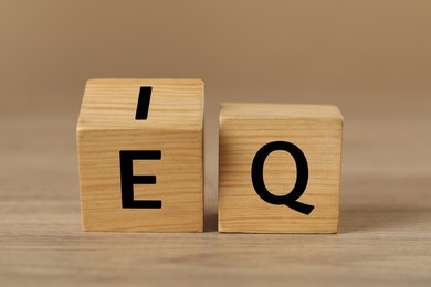 Cubes with letters E, I and Q on wooden table