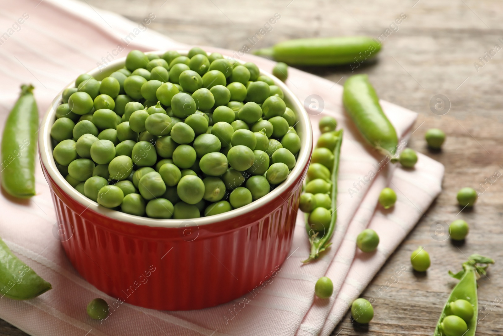 Photo of Bowl with green peas on wooden table