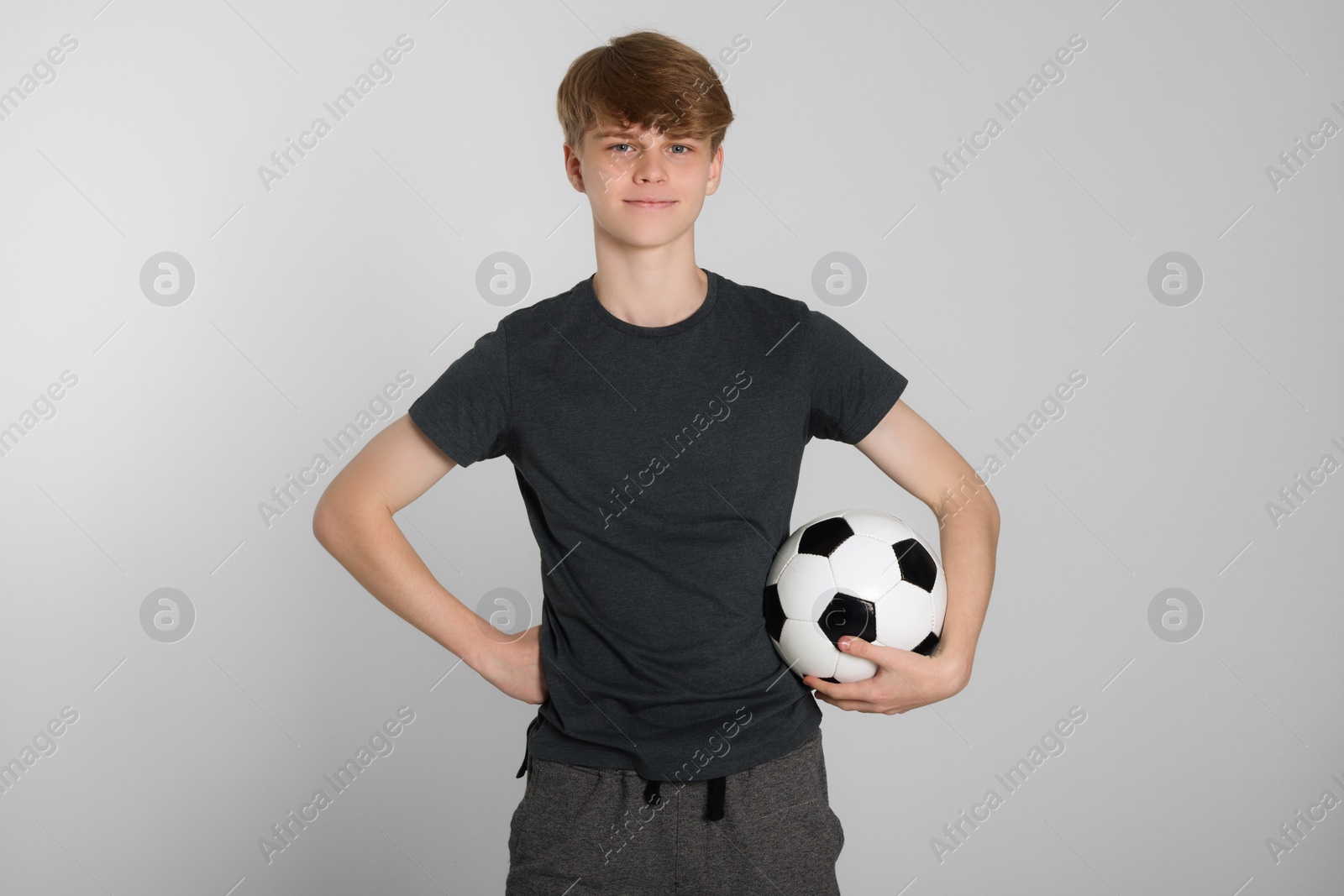 Photo of Teenage boy with soccer ball on light grey background