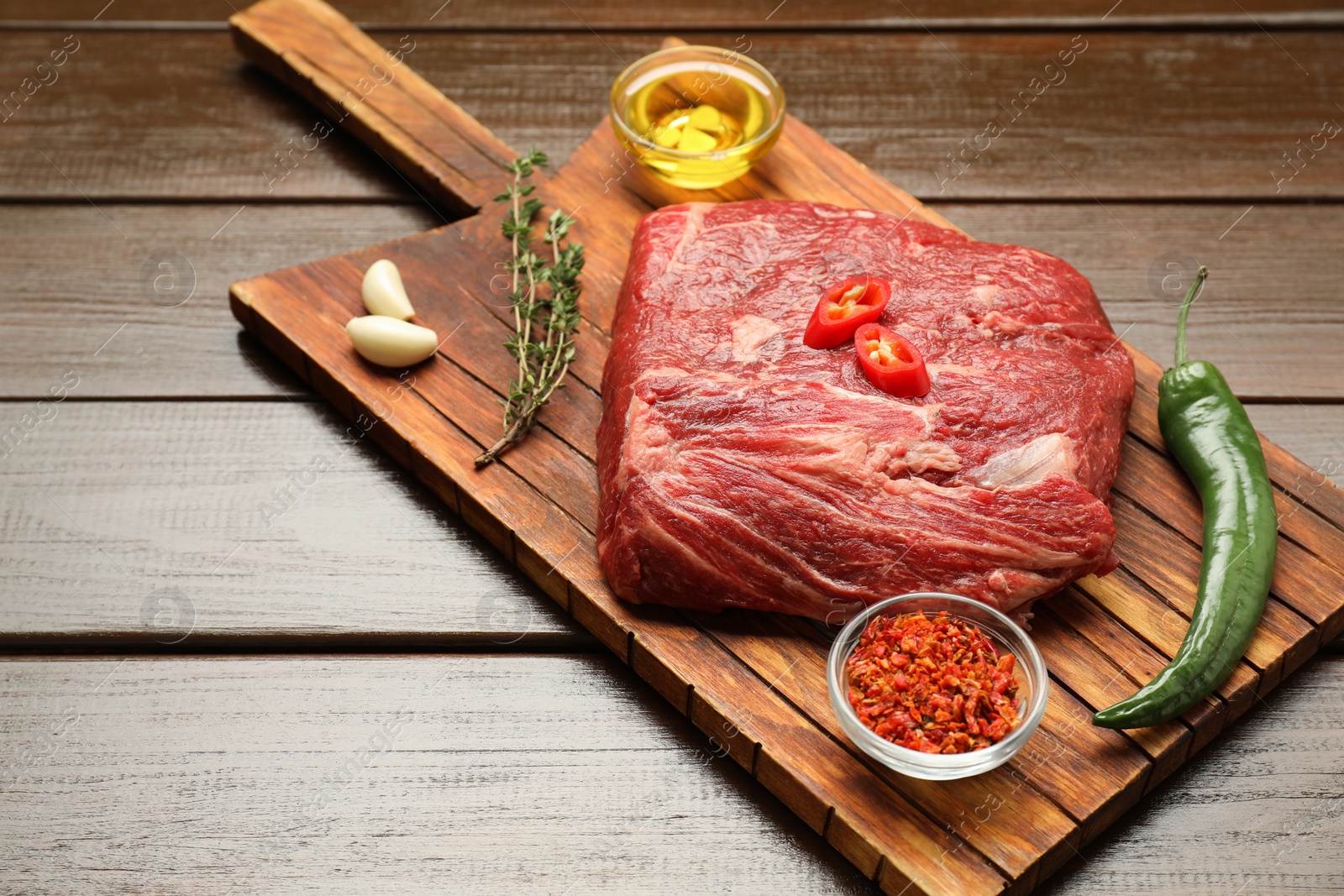 Photo of Fresh raw beef cut, spices and oil on wooden table. Space for text