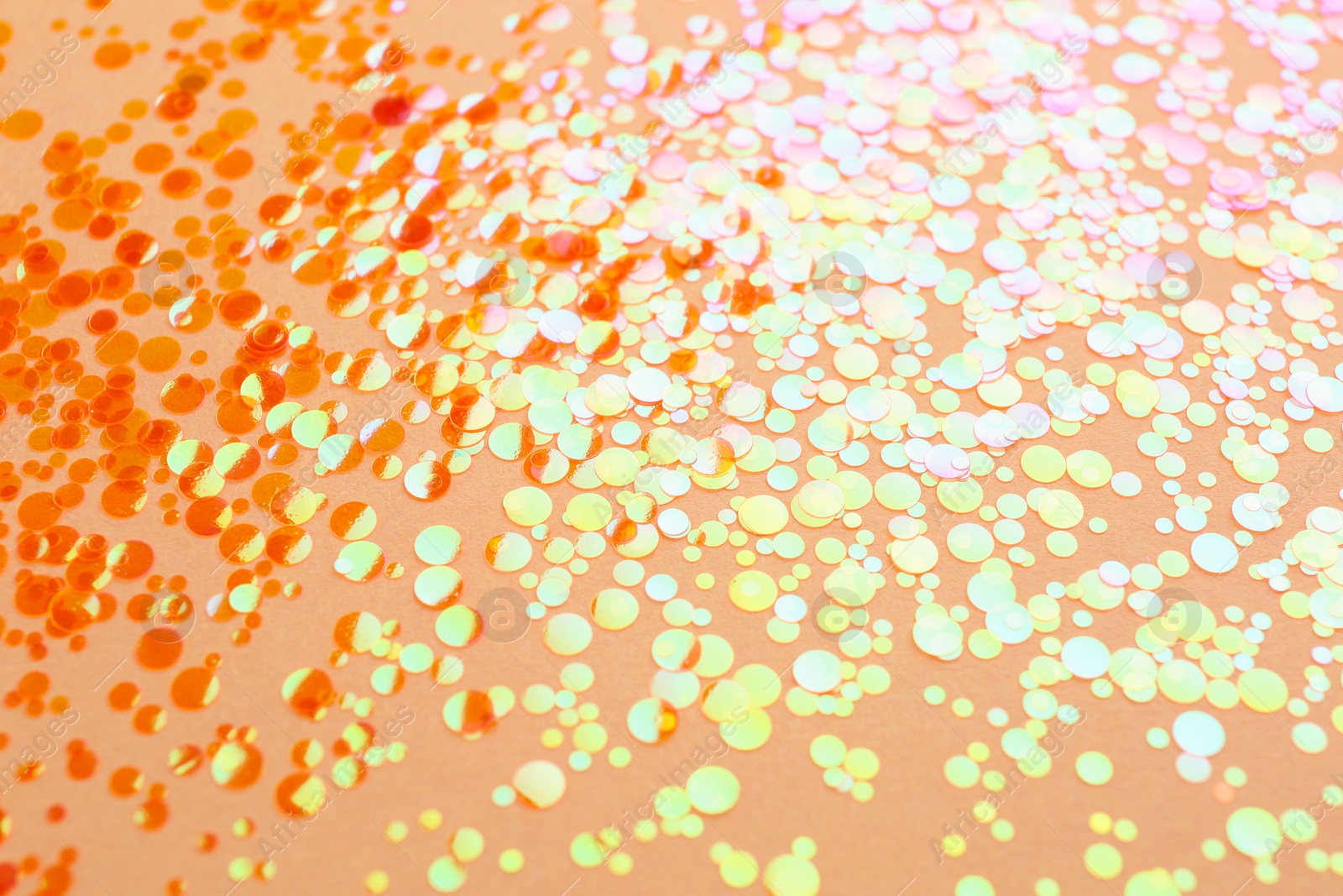 Photo of Shiny bright orange glitter on beige background