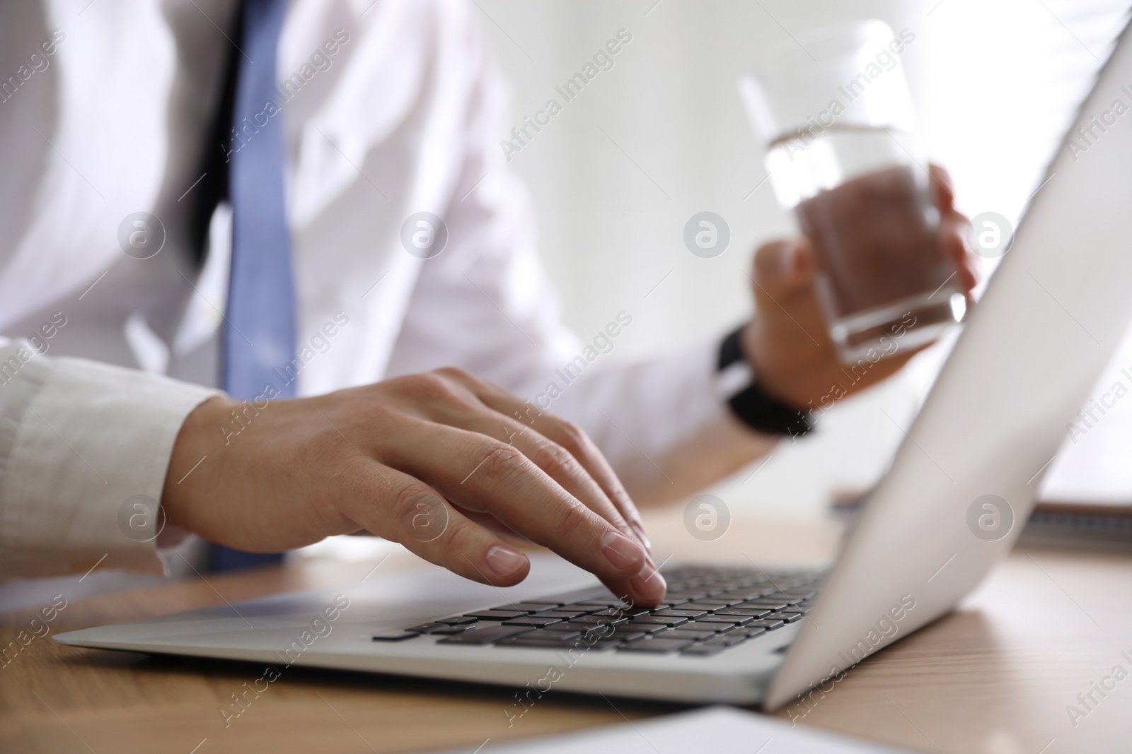 Photo of Man working with laptop in office, closeup of hand