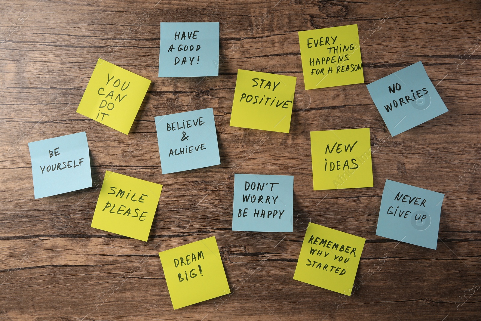 Photo of Paper notes with life-affirming phrases on wooden table, flat lay