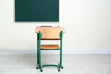Modern empty school desk near chalkboard in classroom