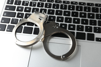 Handcuffs on modern laptop, closeup. Cyber crime