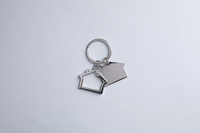 Metallic keychains in shape of houses on light grey background, top view
