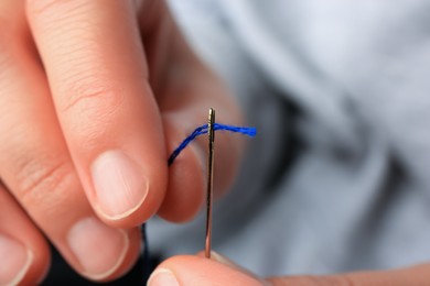 Closeup view of woman threading sewing needle