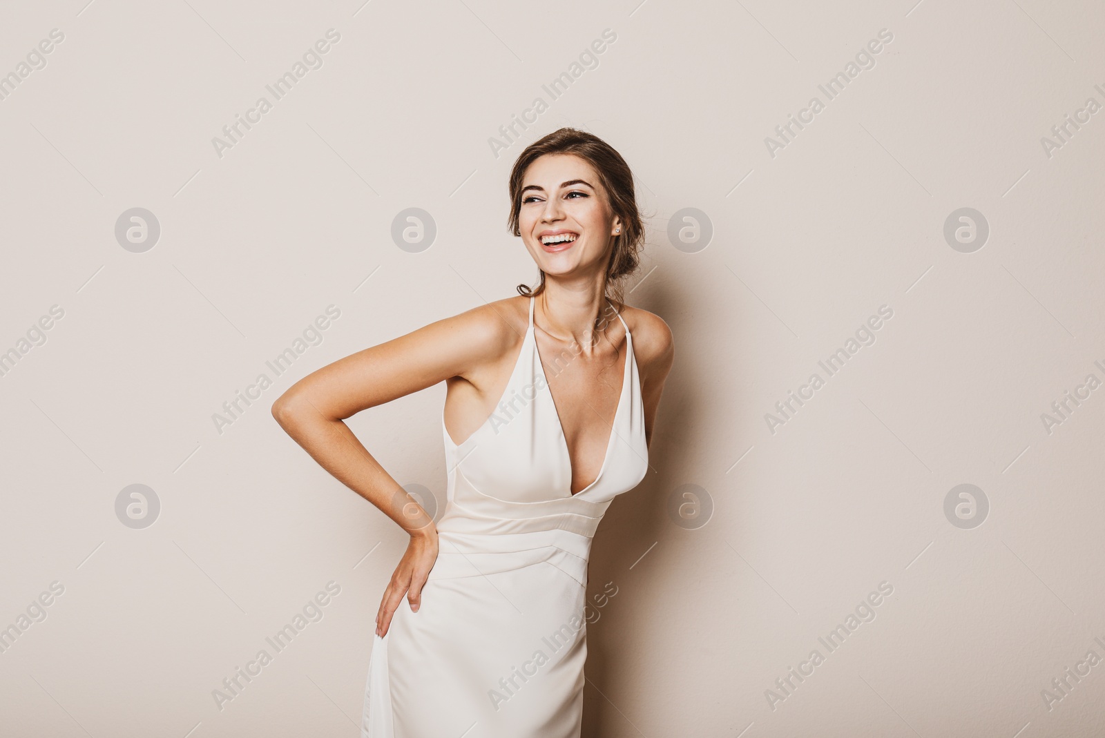 Photo of Young bride wearing beautiful wedding dress on beige background. Space for text