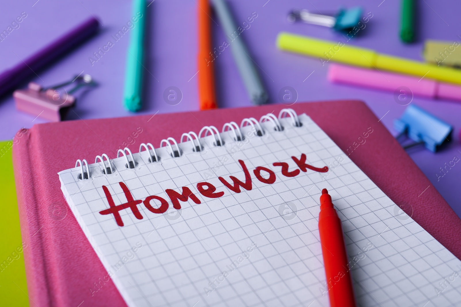 Photo of Word HOMEWORK in notebook on violet table, closeup