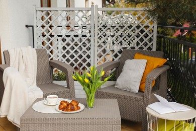 Photo of Different pillows, blanket, breakfast and beautiful tulips on rattan garden furniture outdoors