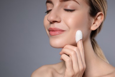 Woman using silkworm cocoon in skin care routine on grey background. Space for text