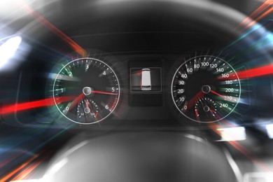 Speedometer and tachometer behind steering wheel in car, motion blur effect
