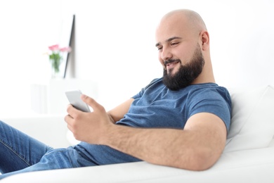 Photo of Portrait of young man with mobile phone on sofa