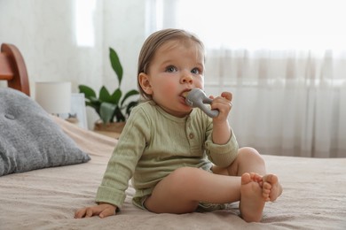 Cute baby girl with nibbler on bed at home