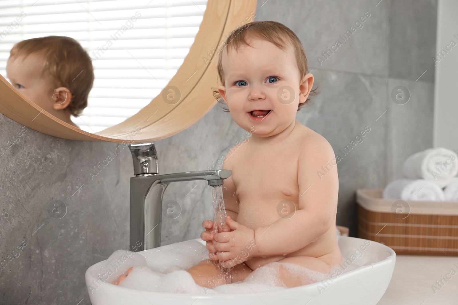 Photo of Cute little baby bathing in sink at home