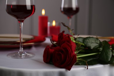 Place setting with roses on white table, closeup. Romantic dinner