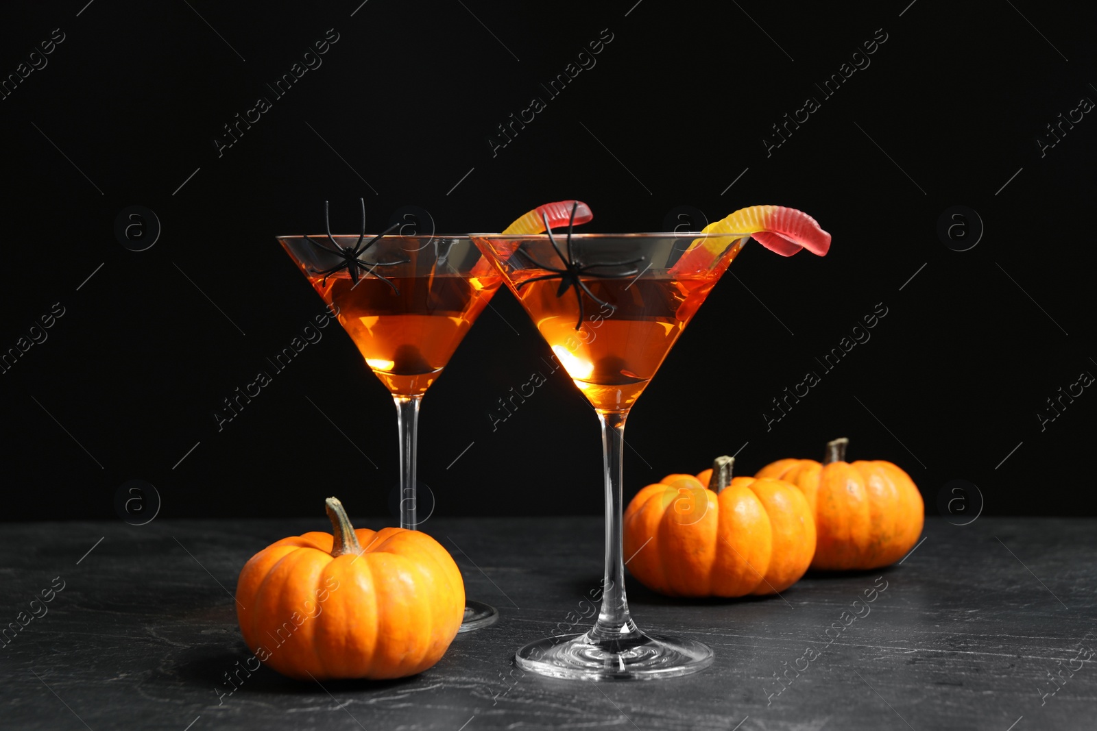 Photo of Decorated glasses with drinks on grey table. Halloween celebration