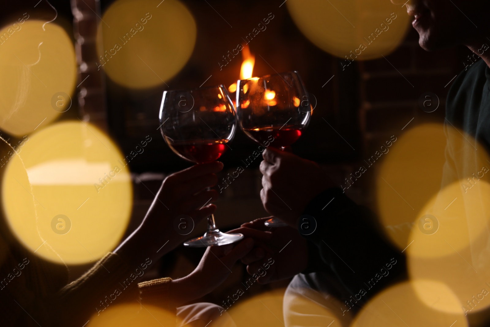 Photo of Couple with glasses of red wine near burning fireplace, closeup