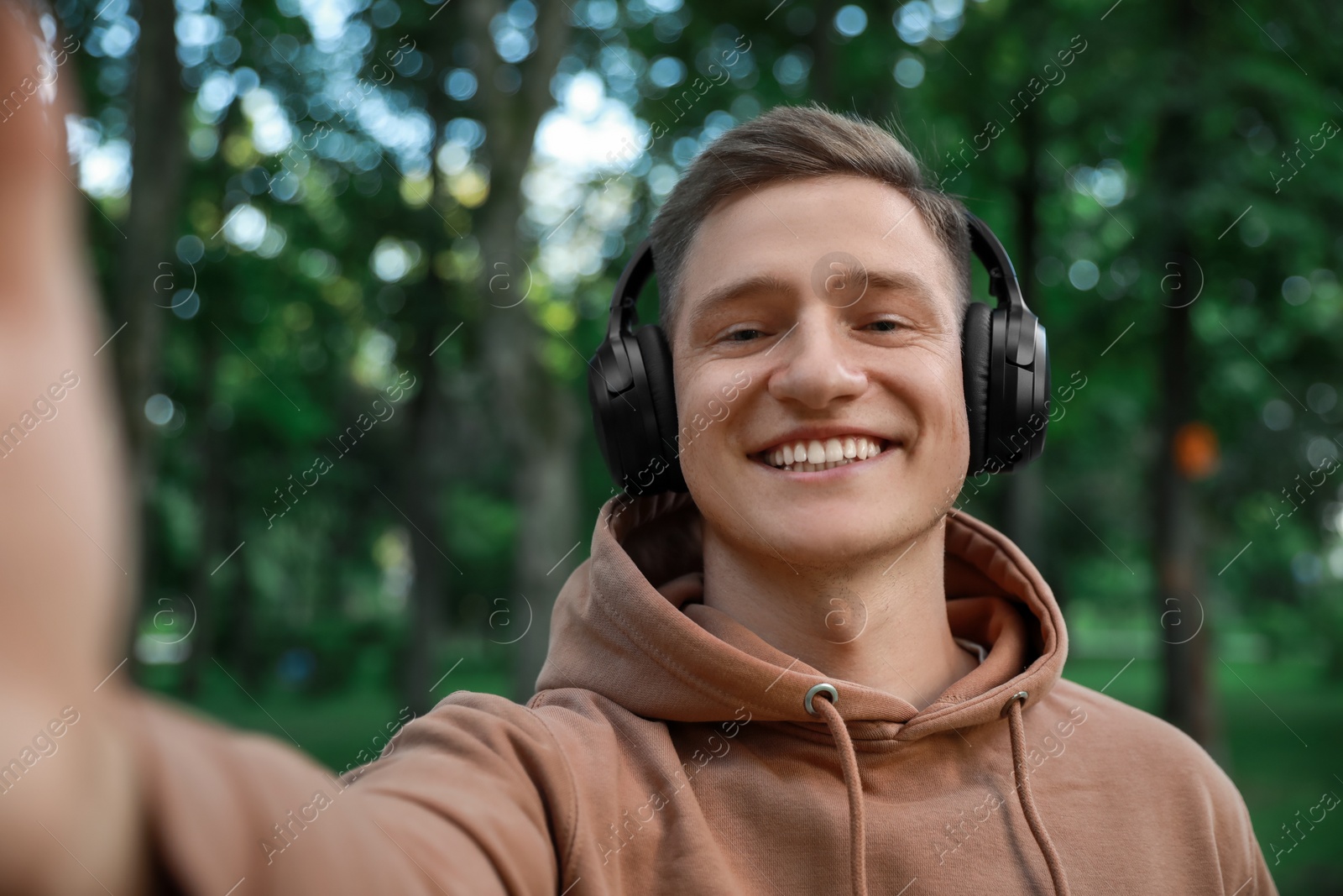 Photo of Smiling man in headphones taking selfie in park