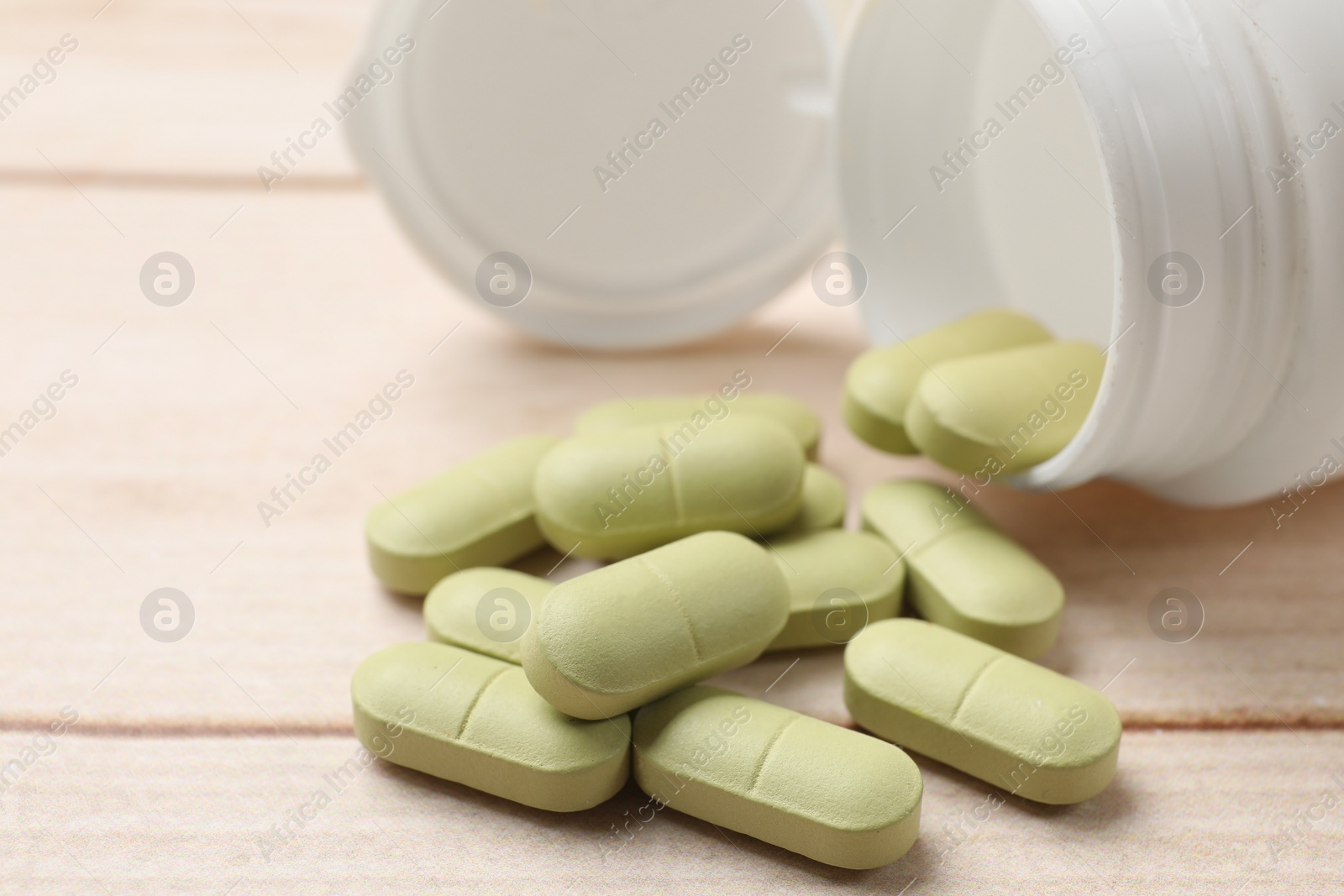 Photo of Bottle and vitamin pills on wooden table, closeup