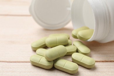 Photo of Bottle and vitamin pills on wooden table, closeup