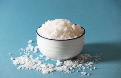 Organic salt in bowl on light blue background, closeup