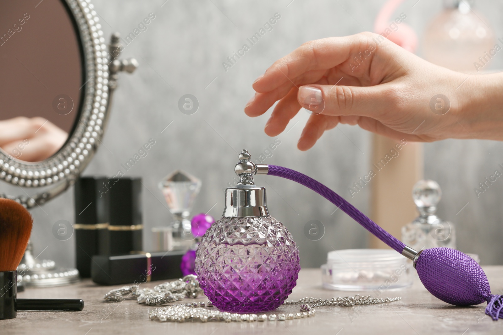 Photo of Woman reaching for crystal bottle of luxurious perfume on dressing table, closeup