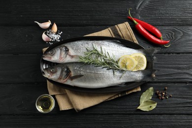 Flat lay composition with tasty sea bass fish on black wooden table