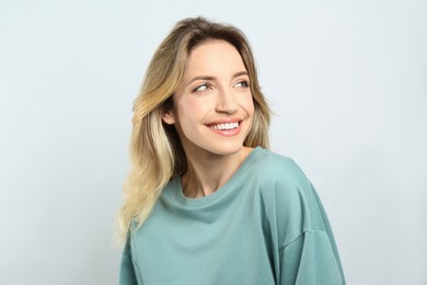 Photo of Portrait of happy young woman with beautiful blonde hair and charming smile on light background
