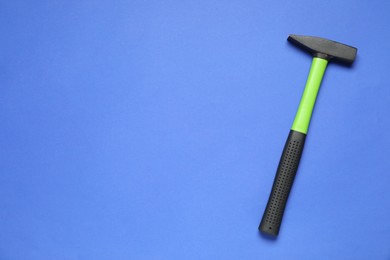 Photo of New hammer with rubber handle on blue background, top view. Space for text