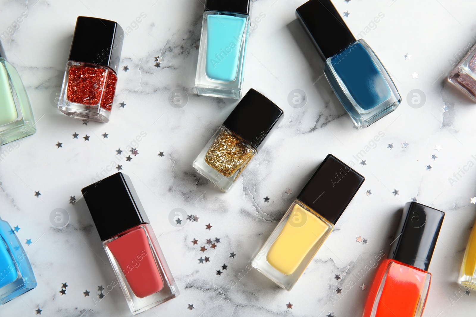 Photo of Bottles of nail polish on marble background, top view