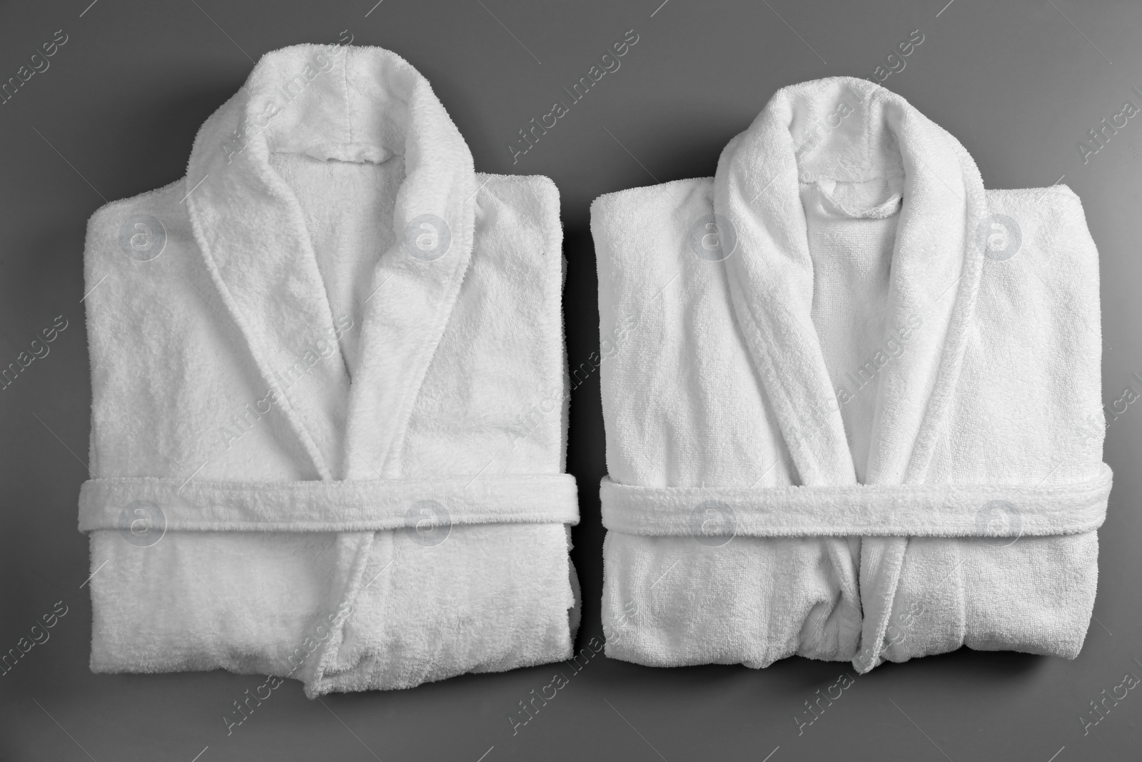 Photo of Clean folded bathrobes on grey background, flat lay