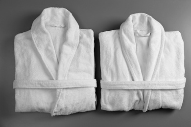 Photo of Clean folded bathrobes on grey background, flat lay