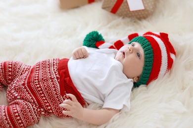 Photo of Adorable baby in Christmas hat on fuzzy rug