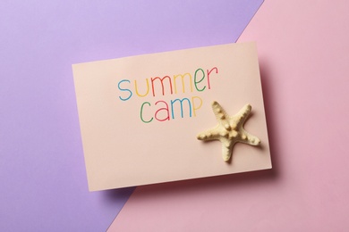 Photo of Card with text SUMMER CAMP and starfish on color background, top view