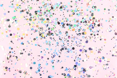 Photo of Shiny glitter on light pink background, top view