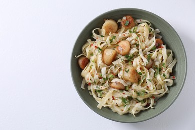 Photo of Delicious scallop pasta with spices in bowl on white table, top view
