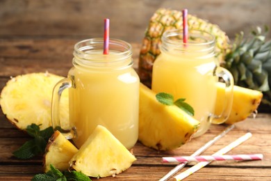 Photo of Delicious pineapple juice and fresh fruit on wooden table