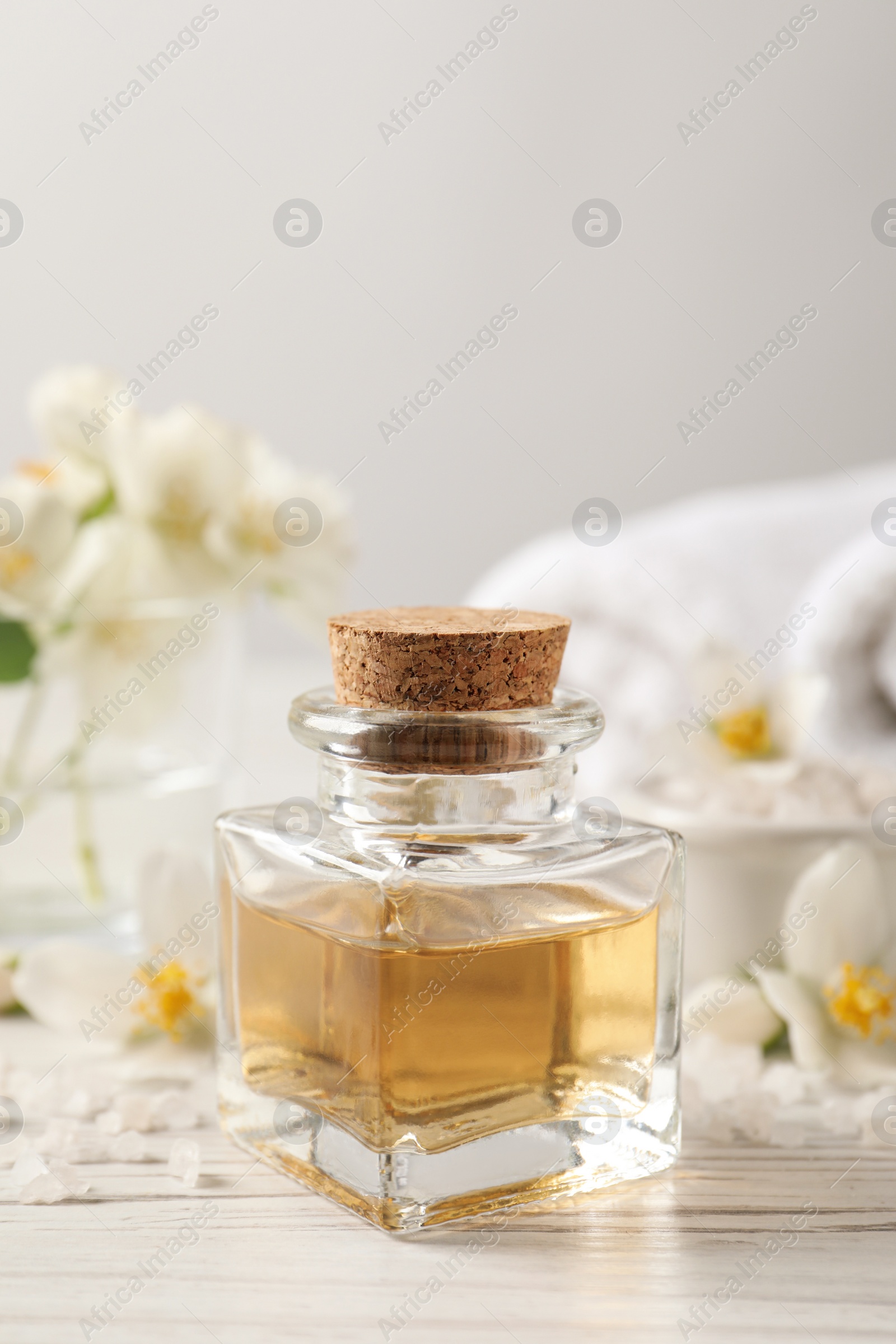 Photo of Beautiful composition with jasmine essential oil and fresh flowers on white wooden table