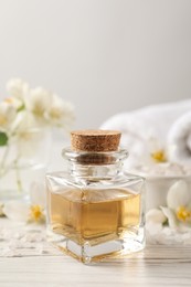 Beautiful composition with jasmine essential oil and fresh flowers on white wooden table