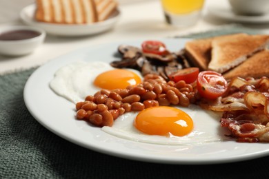 Photo of Plate with fried eggs, mushrooms, beans, tomatoes, bacon and toasts on table, closeup. Traditional English breakfast