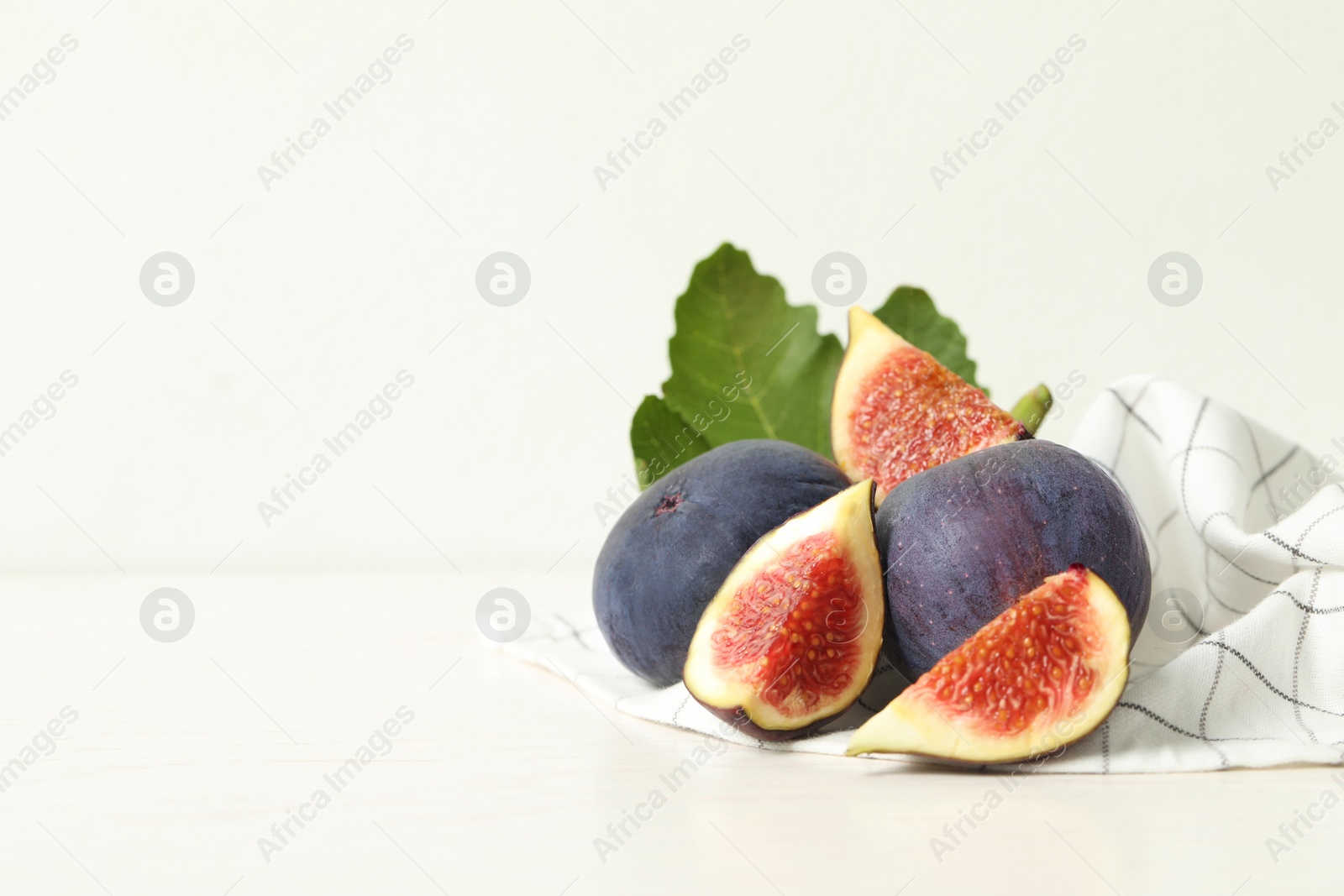 Photo of Whole and cut tasty fresh figs on white table, space for text