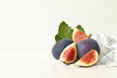 Whole and cut tasty fresh figs on white table, space for text
