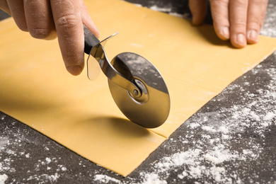 Woman making pasta at grey table, closeup