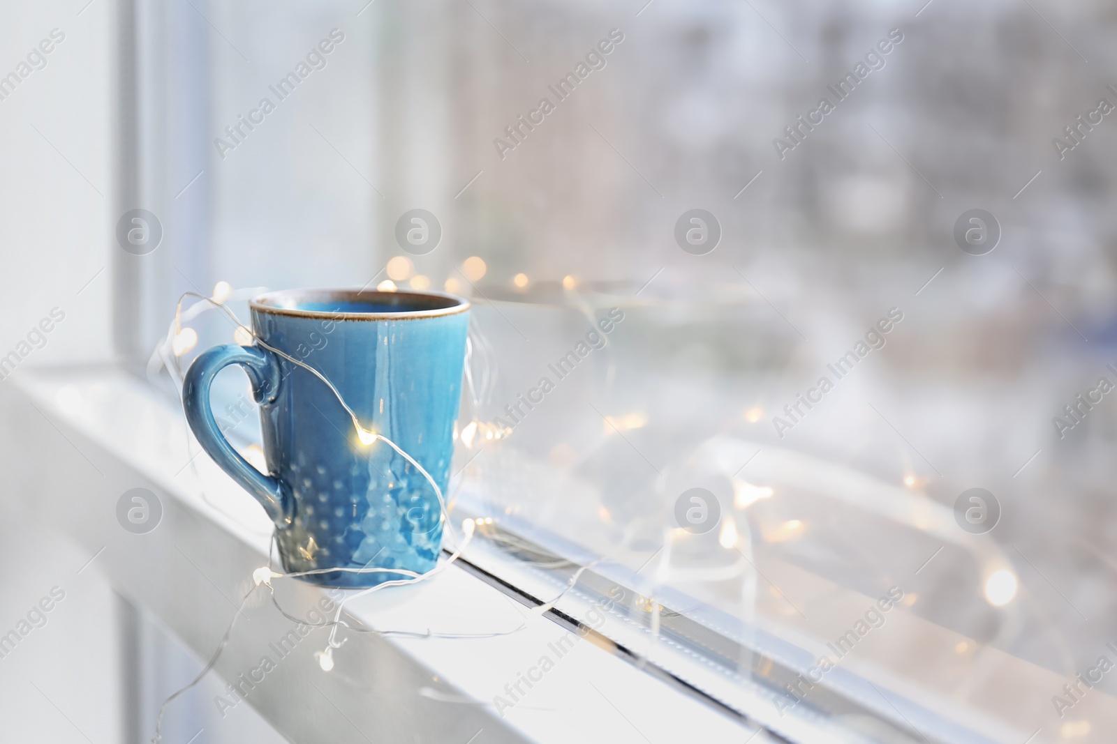 Photo of Cup of hot coffee near window indoors
