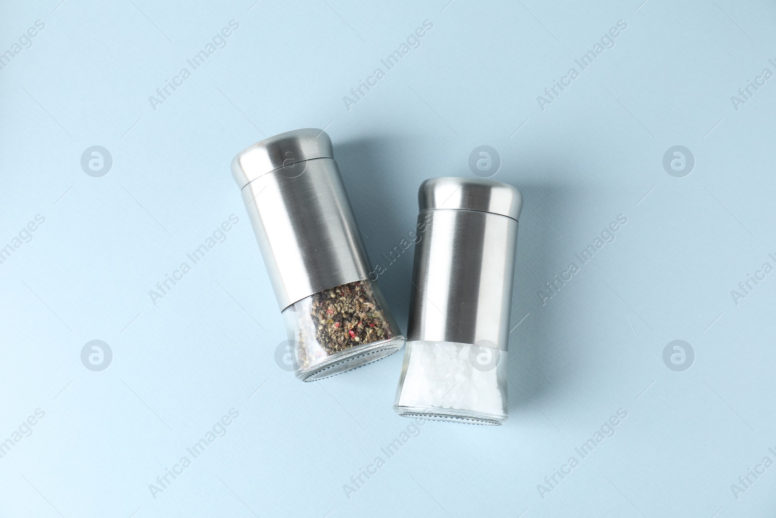 Photo of Salt and pepper shakers on light background, top view