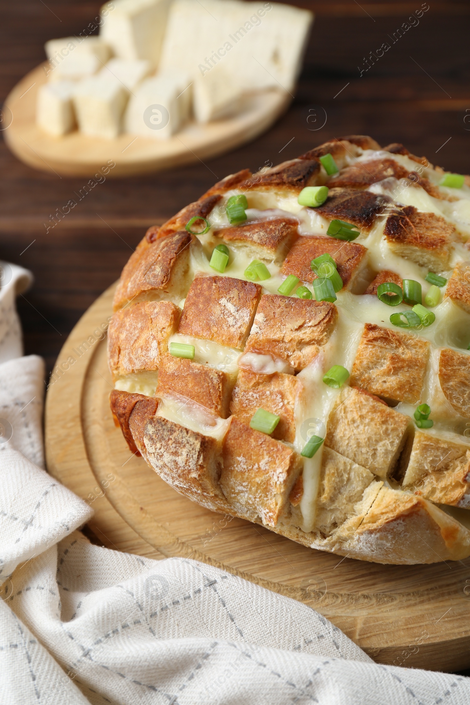 Photo of Freshly baked bread with tofu cheese and green onions on wooden table