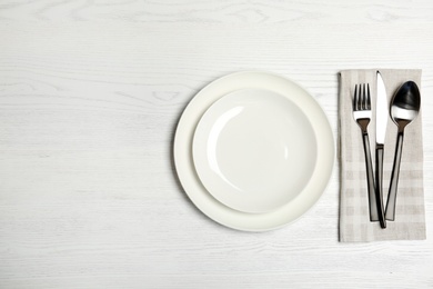 Photo of Plates and cutlery on wooden table, top view. New setting