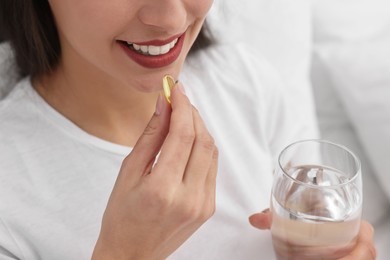 Photo of Woman taking vitamin pill at home, closeup